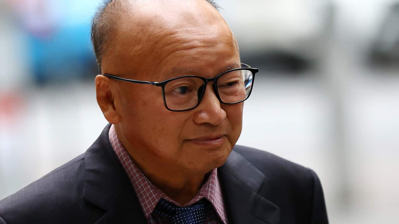 A man wearing a suit and glasses arrives at court.