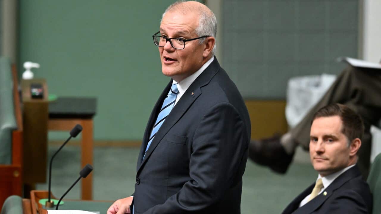 A man wearing a suit delivers a speech.