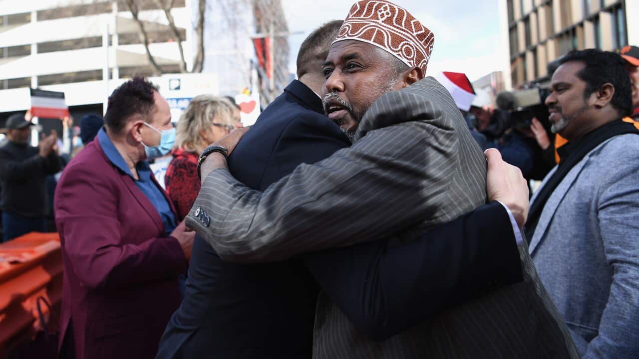 Two men hugging on the street in a crowd.
