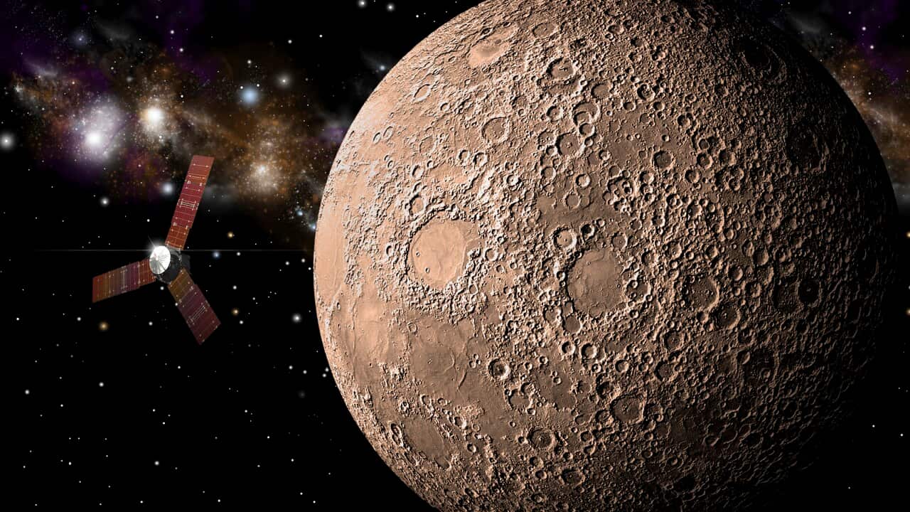 An artist's depiction of a probe investigating a heavily cratered moon in deep space.