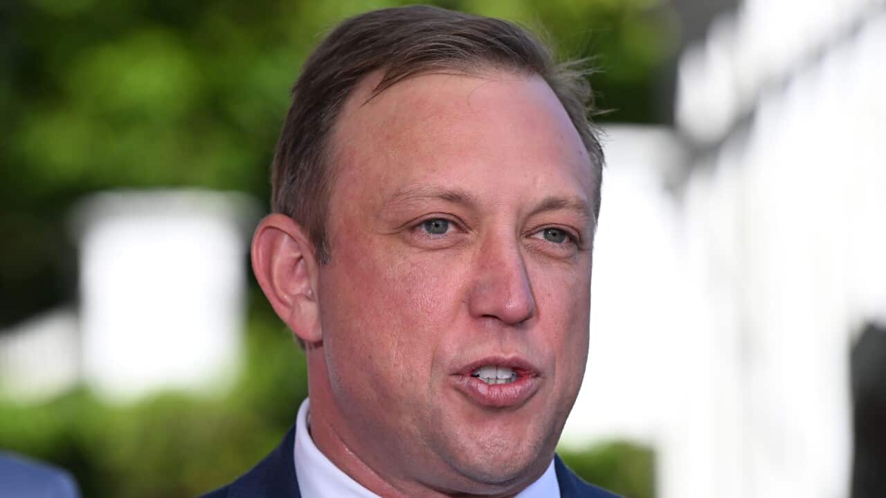 Steven Miles speaking in front of a blurry background of trees and white fence.