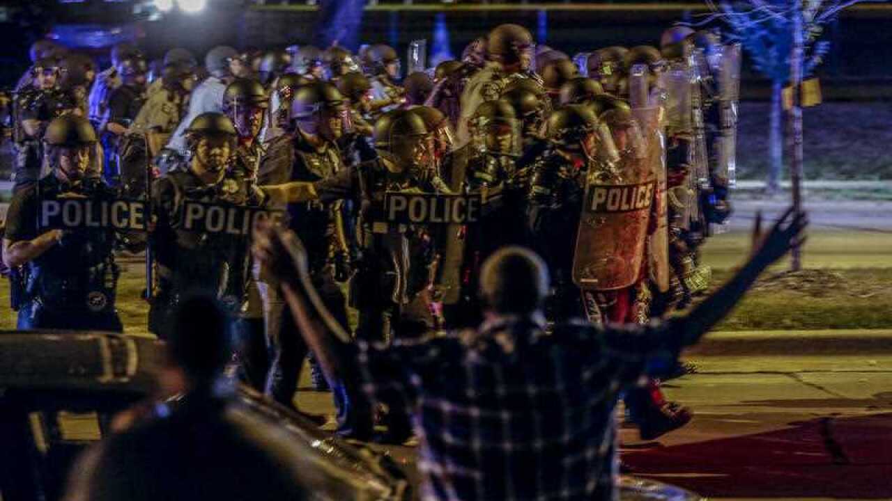 Police move in on a group of protesters throwing rocks at them in Milwaukee, Sunday, Aug. 14, 2016.