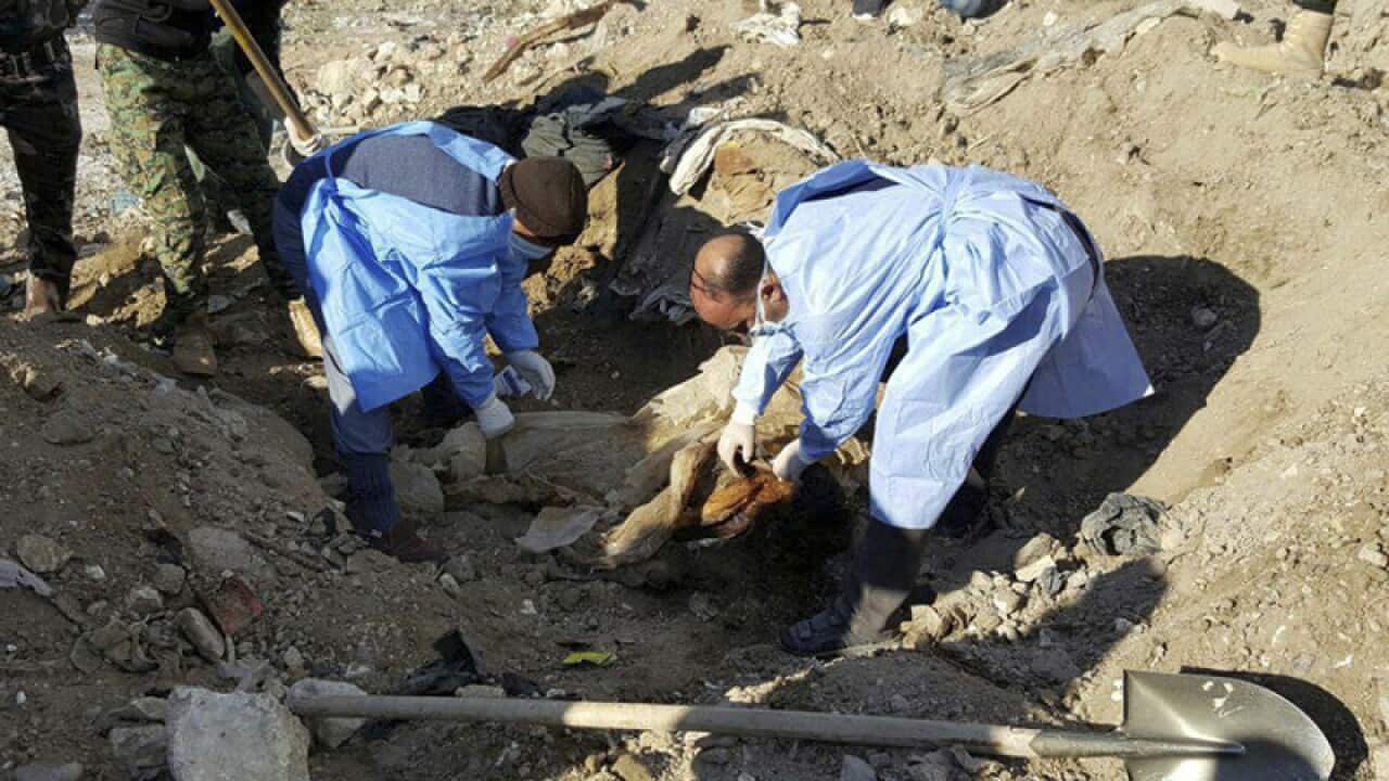 Forensic team members work at the site of a mass grave in Ramadi