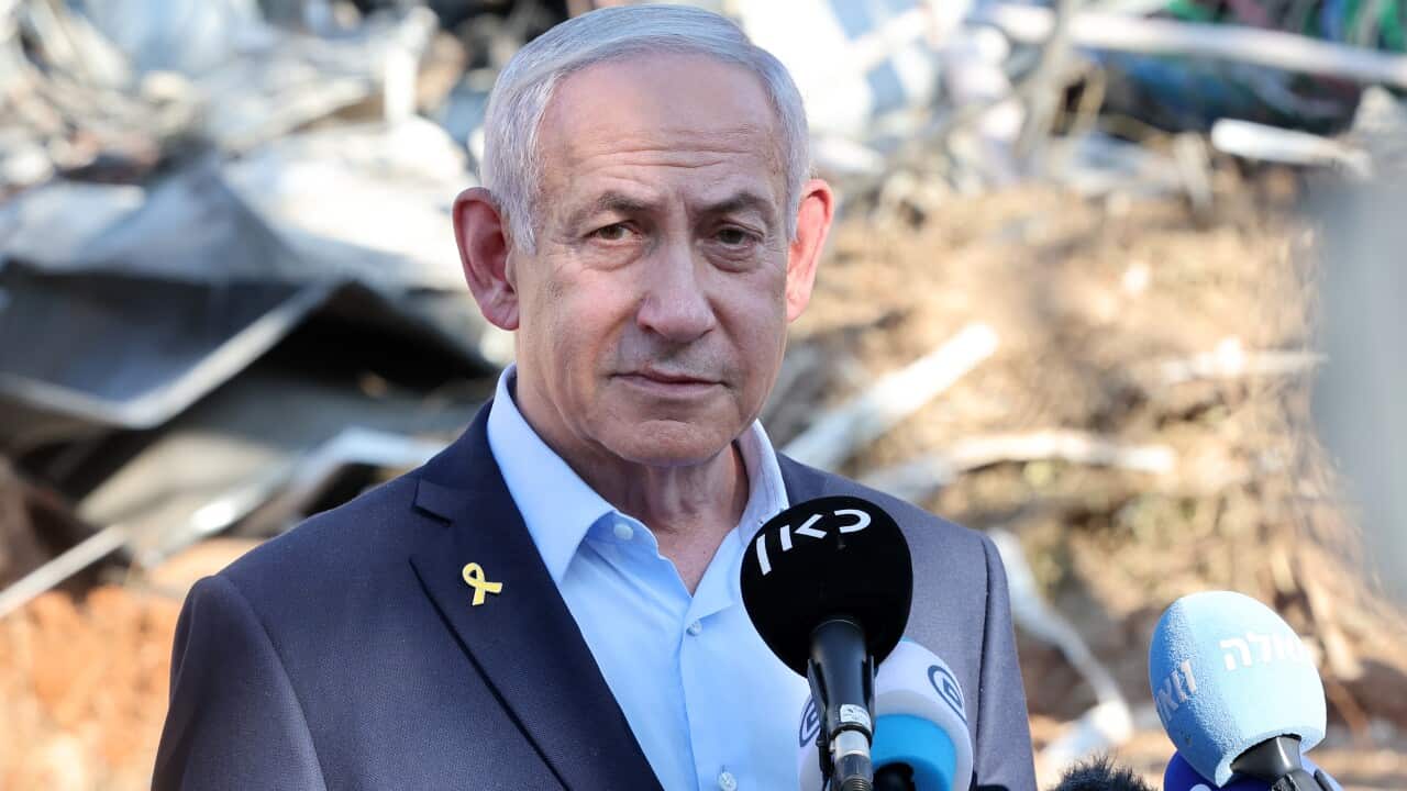 Benjamin Netanyahu, speaking into media microphones.