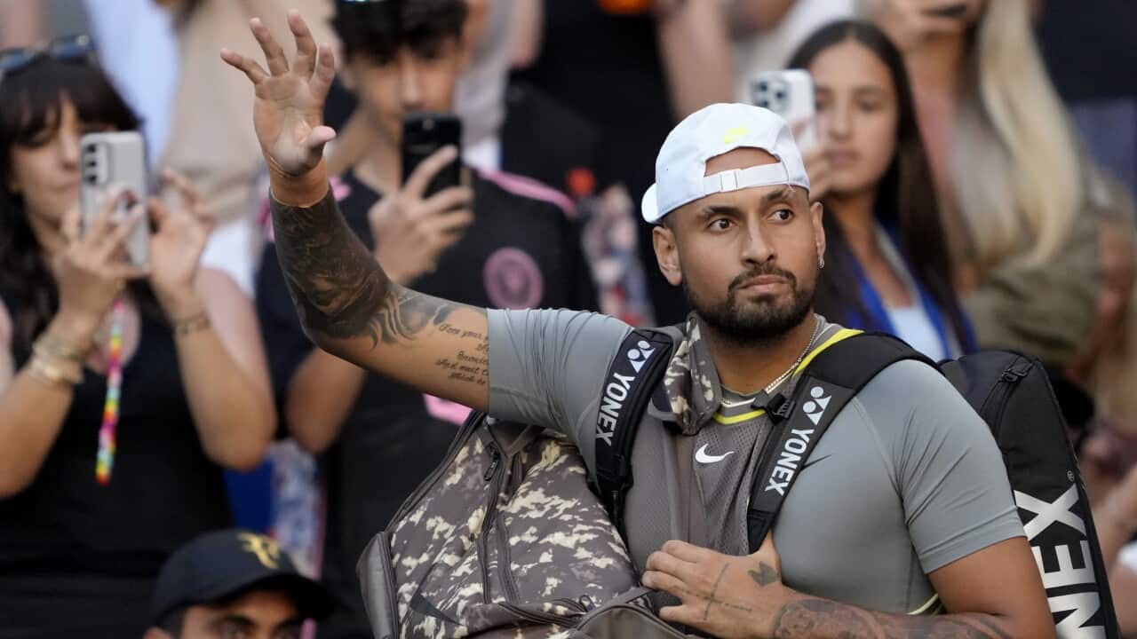 A tennis player carrying bags on a court