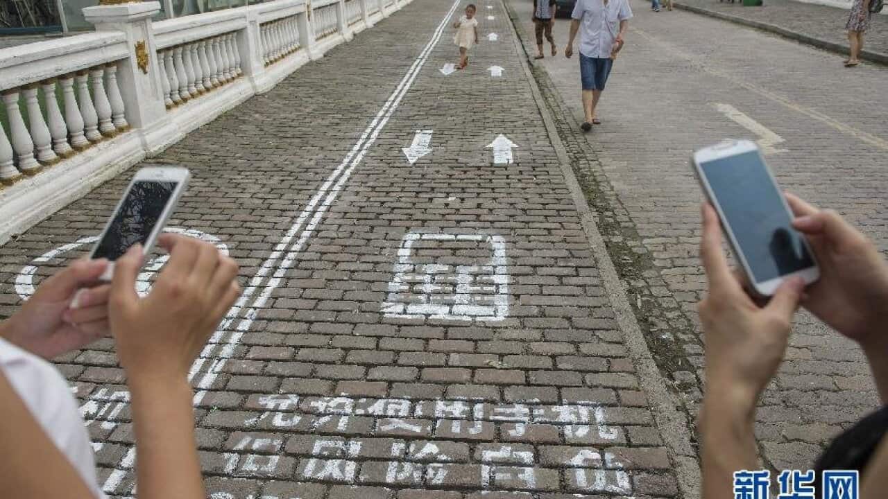 Pedestrians use mobile phone lanes on Foreigner Street in Chongqing, China. The city created mobile phone-specific lanes to reduce collisions and accidents in busy areas. (Image: Xinhua News Agency)