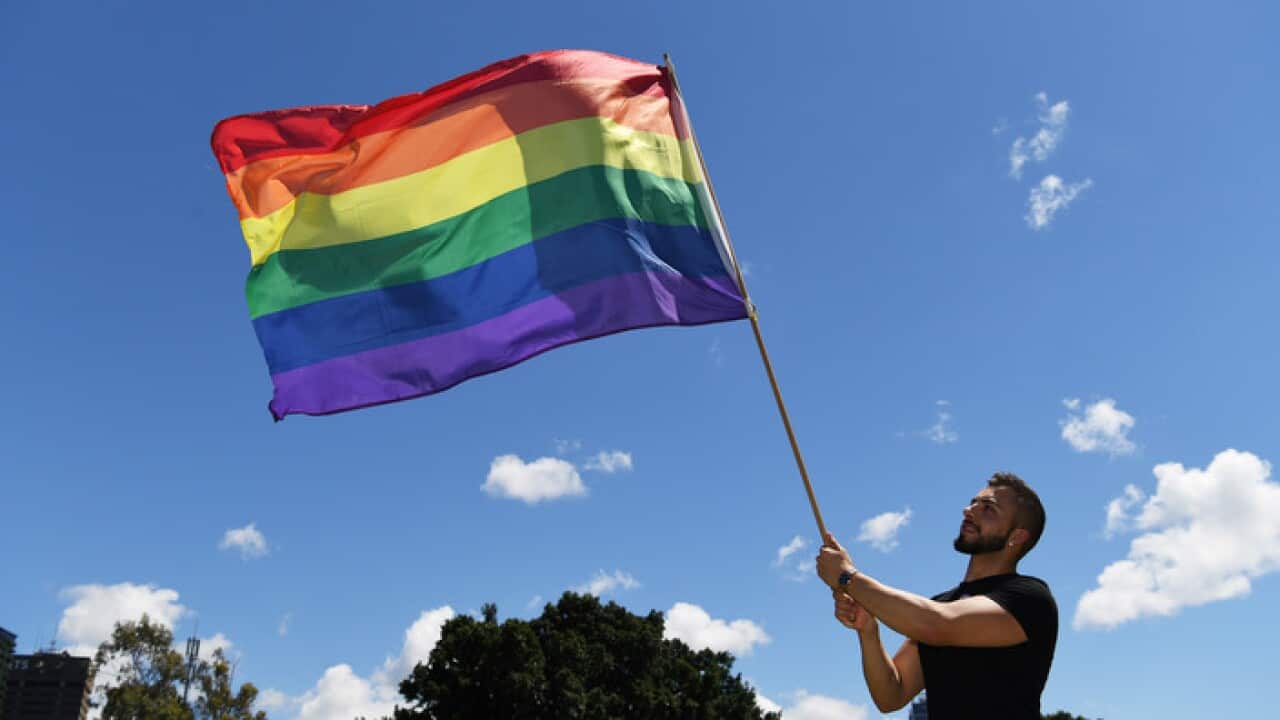 A man holds a rainbow flag as he celebrates after watching the marriage vote result announcement.