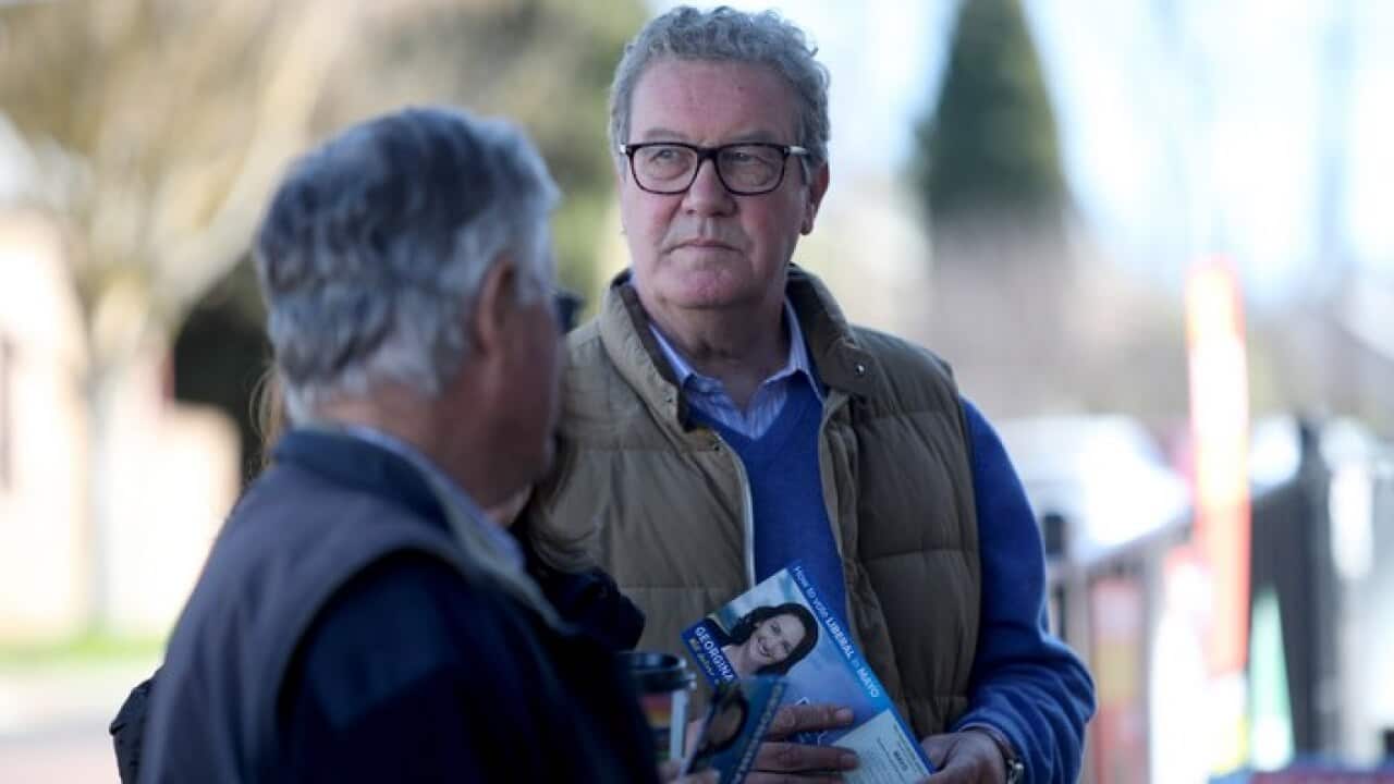 Alexander Downer handing out how-to-vote cards in July