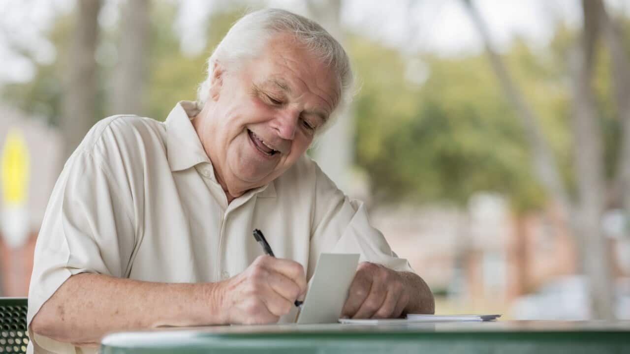 Senior adult man writing letter.