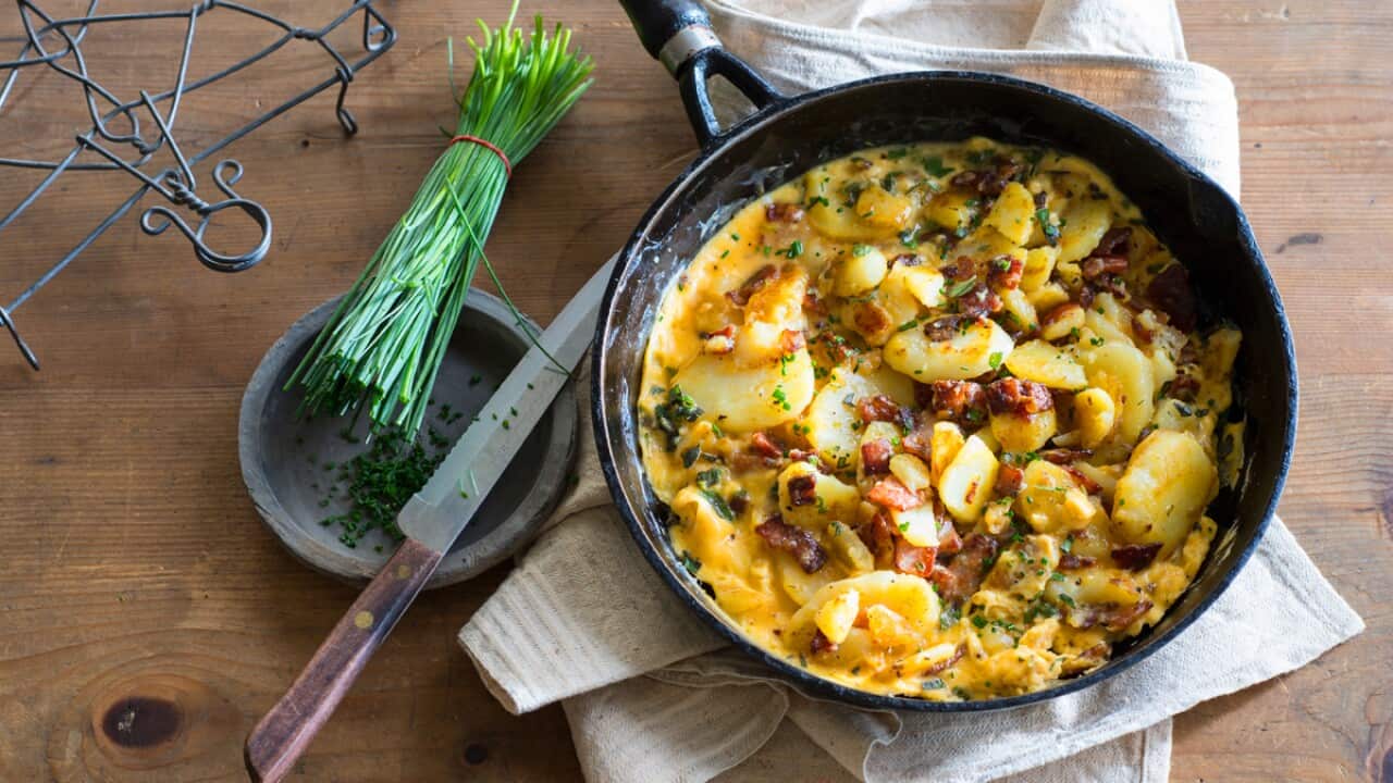 German farmer's breakfast with golden potatoes, bacon, and eggs in a pan