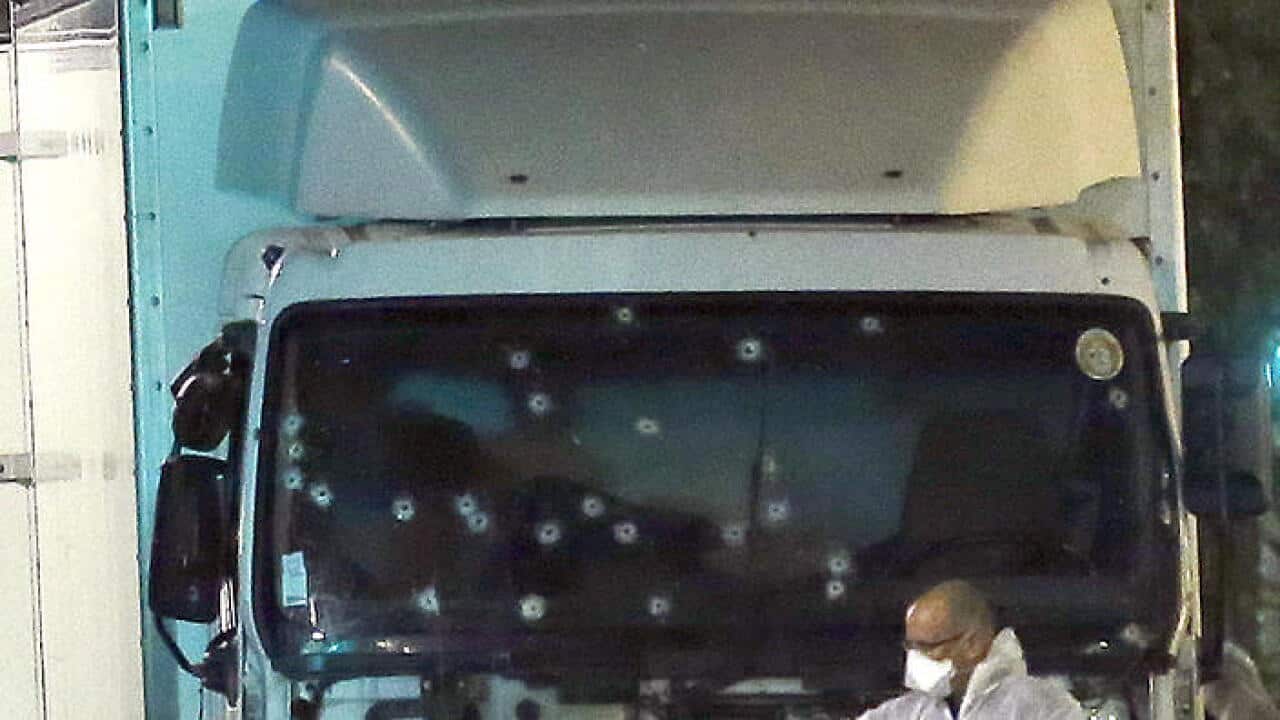 A forensic officer stands near a van with its windscreen riddled with bullets. (AAP)
