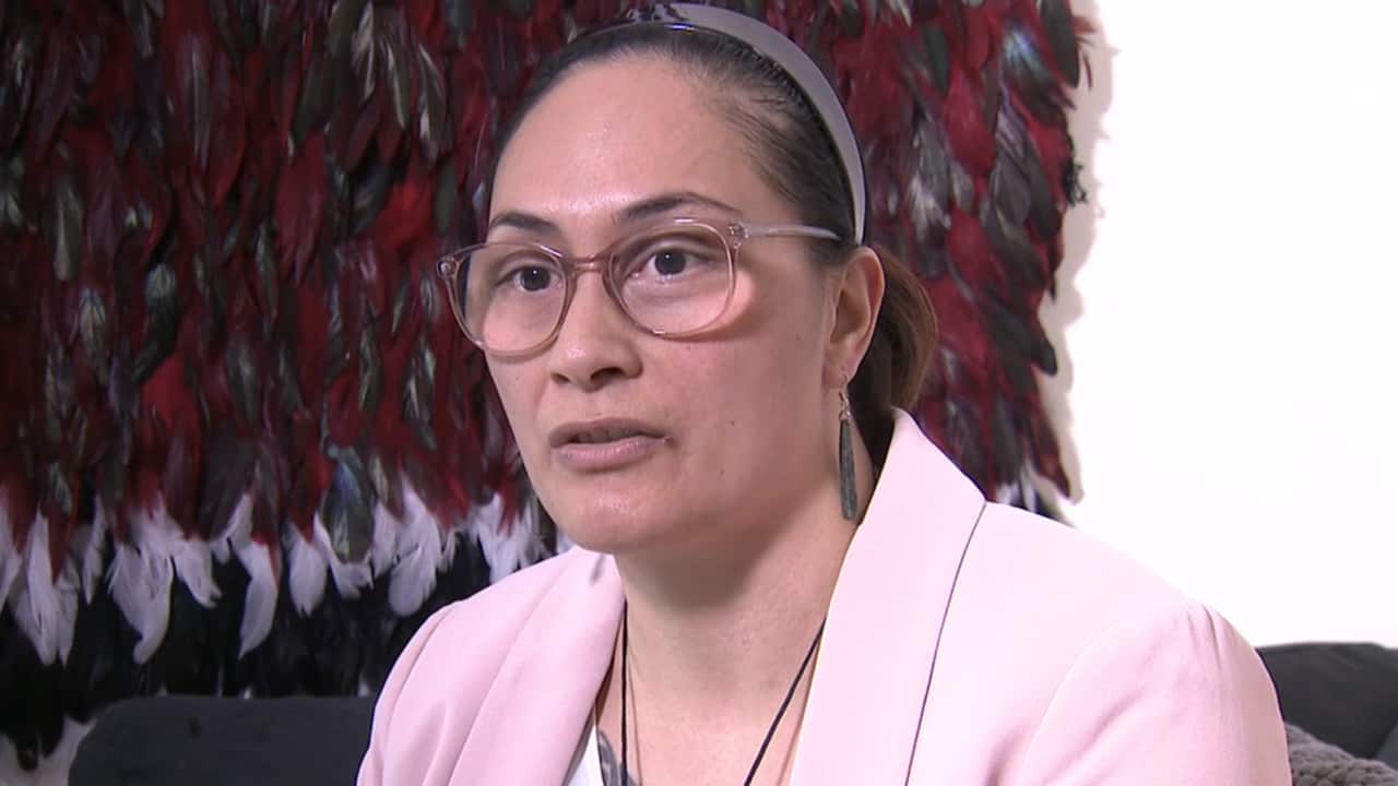 A woman with glasses and a pink blazer