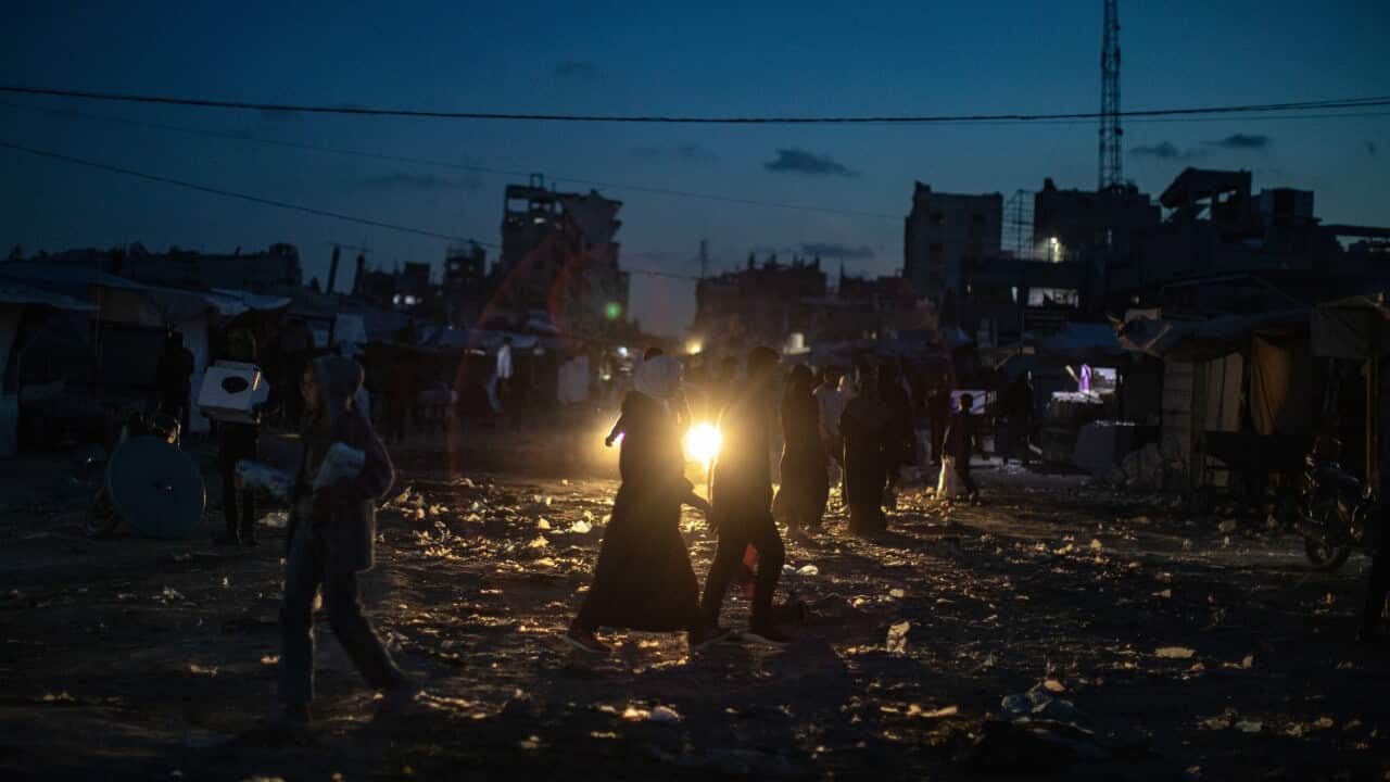 : Palestinians walk at dusk during a power outage in the Jabalia refugee camp, northern Gaza Strip
