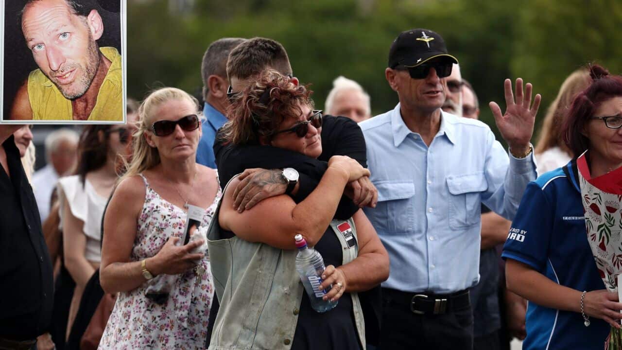 Friends and family embrace at a funeral service.