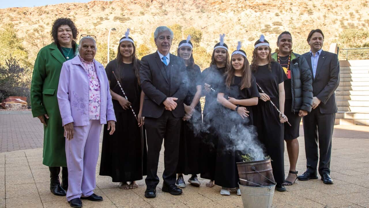 A group of people stand behind a bucket that has coming out of it