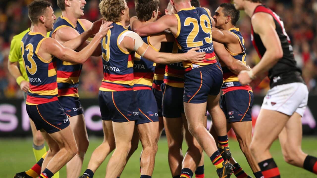 Kyle Hartigan of the Crows is congratulated by team mates