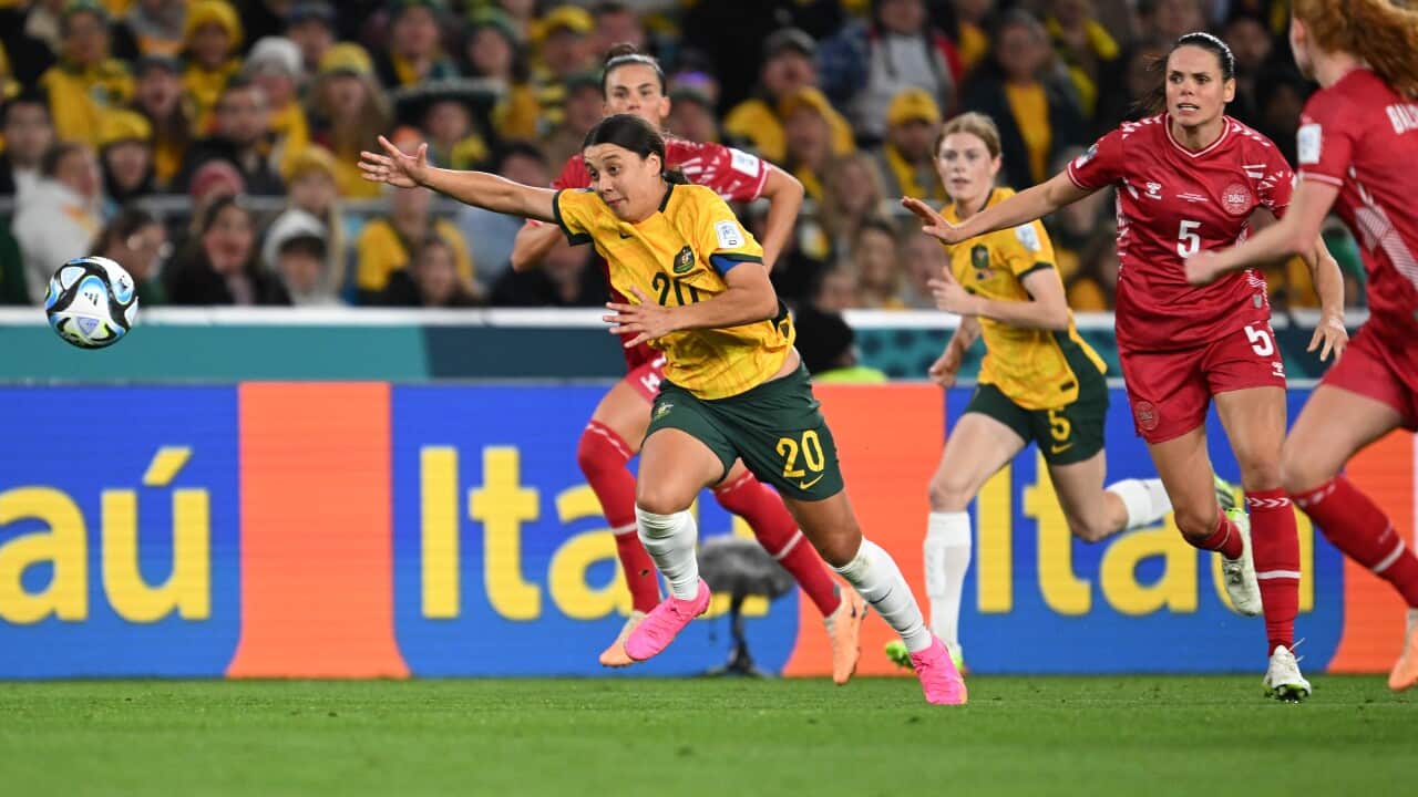 A football player in green and gold jersey chases down the ball.