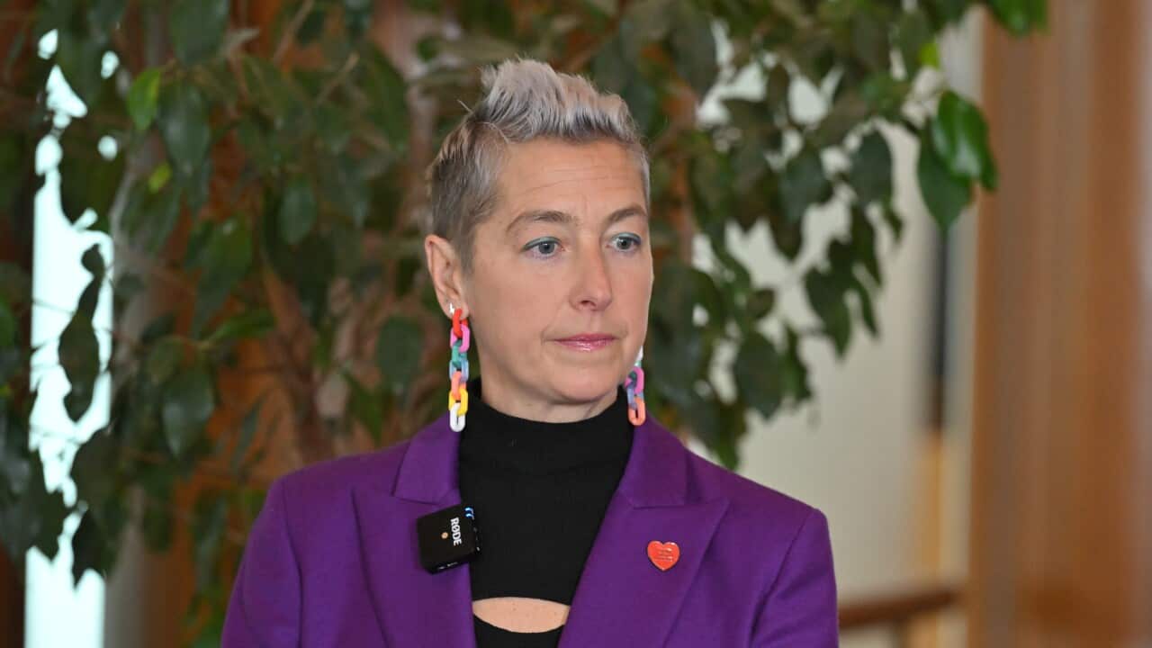 A woman in a purple blazer with a red heart on it.