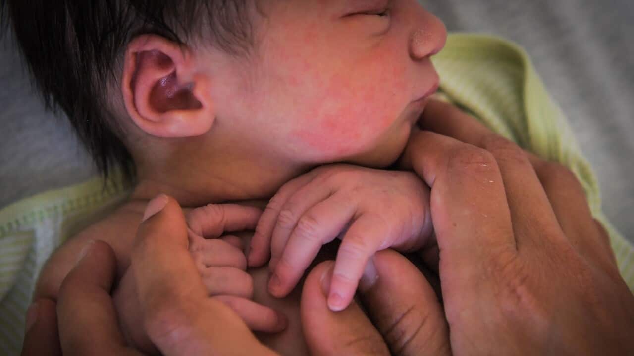 A mother holds her newborn baby