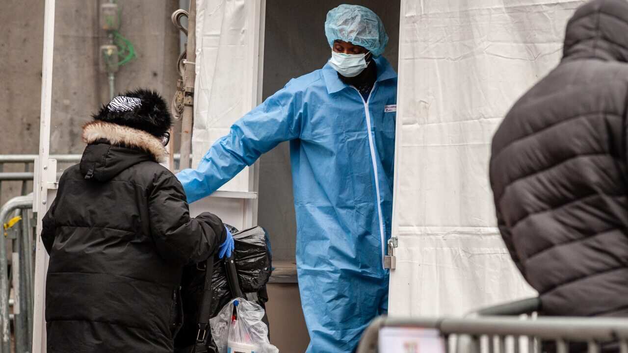 A staffer of The Brooklyn Hospital Center opens the door for a woman entering the outdoor tent facility where patients are pre-screened for the Coronavirus in Brooklyn, New York on March 19, 2020. (Photo by Gabriele Holtermann-Gorden/Sipa USA)