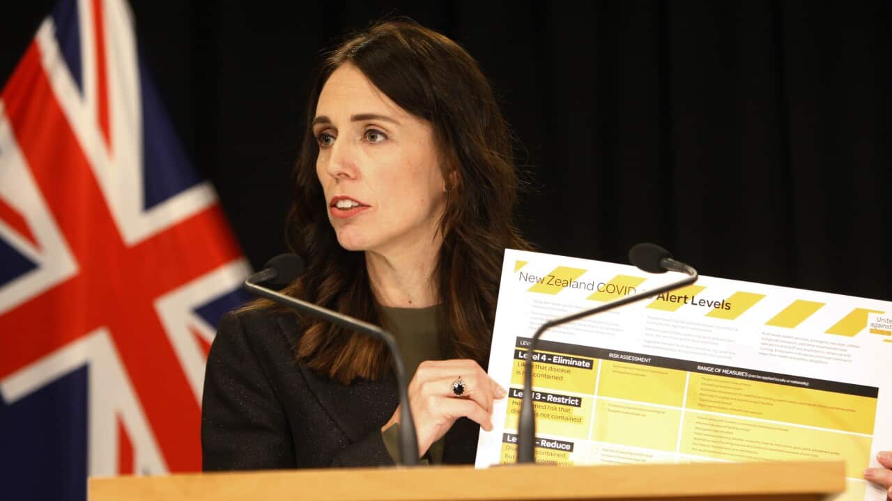New Zealand Prime Minister Jacinda Ardern holds up a card showing a new alert system for COVID-19, Saturday, March 21, 2020, in Wellington