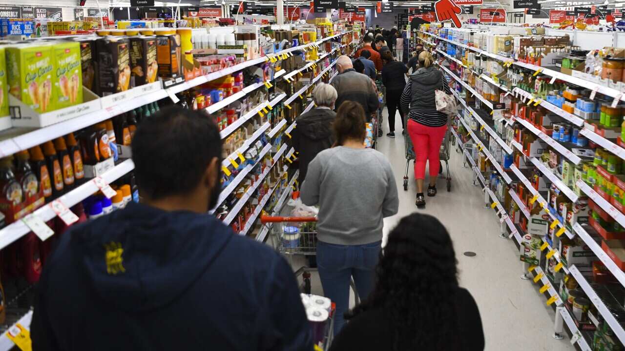 Customers stand in long lines at a check out counter at a Coles supermarket in the Woden area in Canberra, Thursday, August 12, 2021. The ACT is going into a 7 day lockdown after the discovery of the first local COVID-19 case in over a year. (AAP Image/Lu