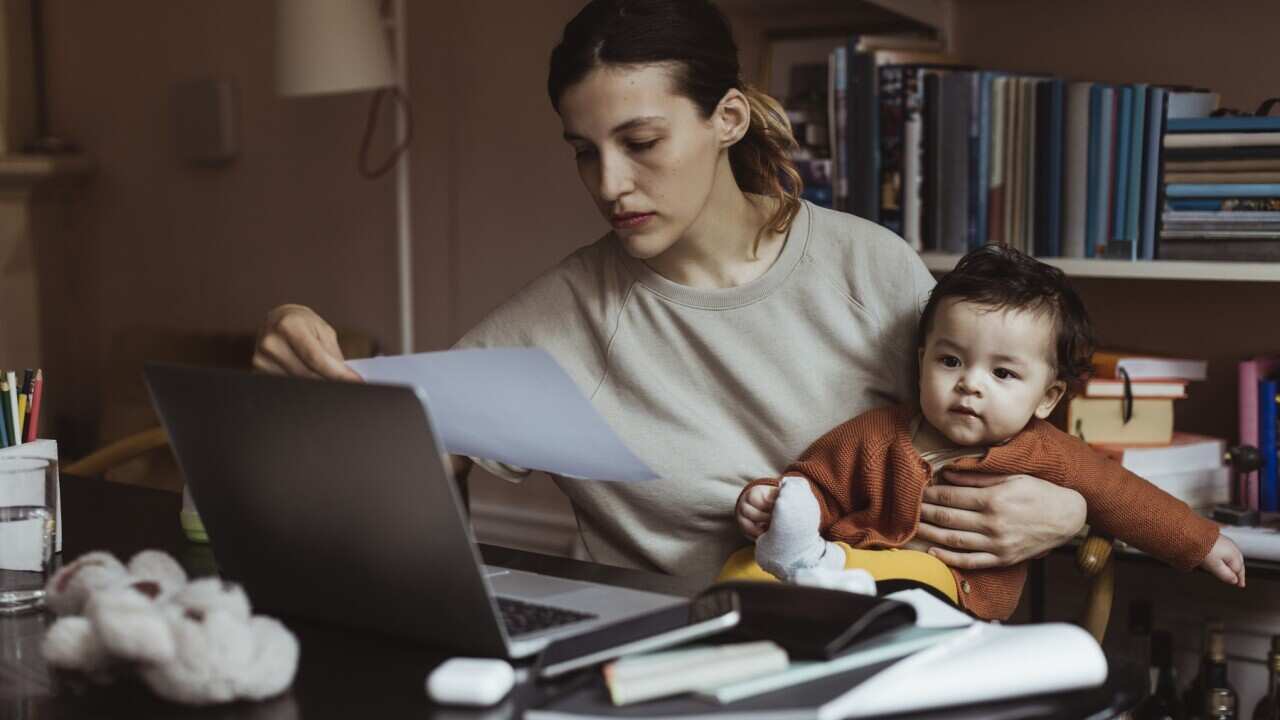 Female professional reading document while sitting with male toddler at home