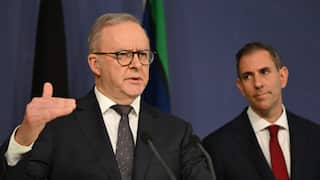 Anthony Albanese in a black suit standing next to Jim Chalmers in a black suit and red tie