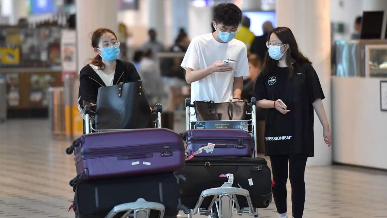 People wearing protective face masks are seen at Brisbane International Airport on Wednesday.