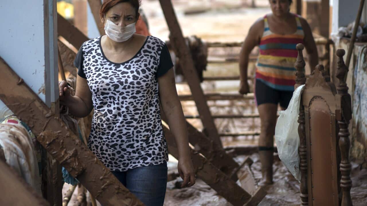 People stand in their damaged home in Barra Longa