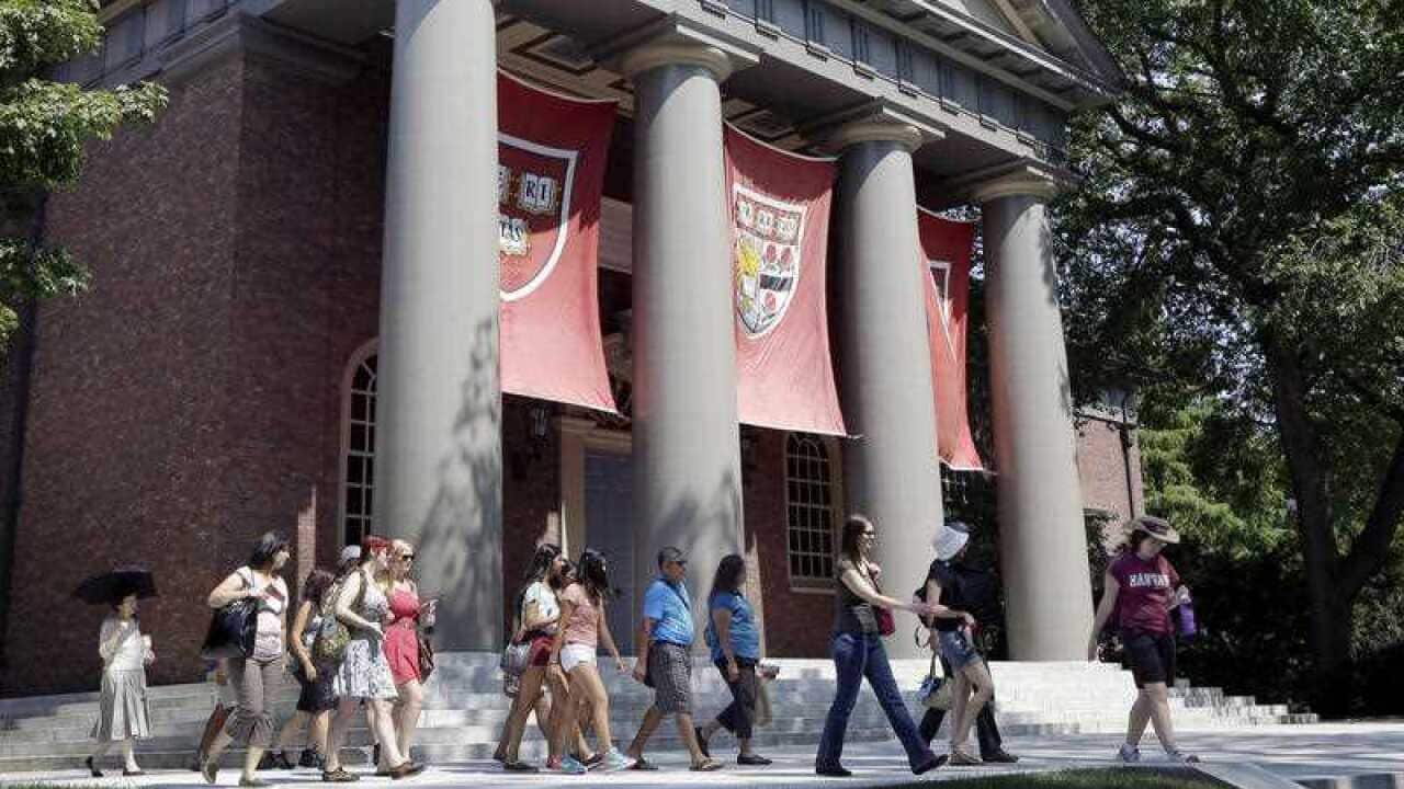A tour group walks through the campus of Harvard University.