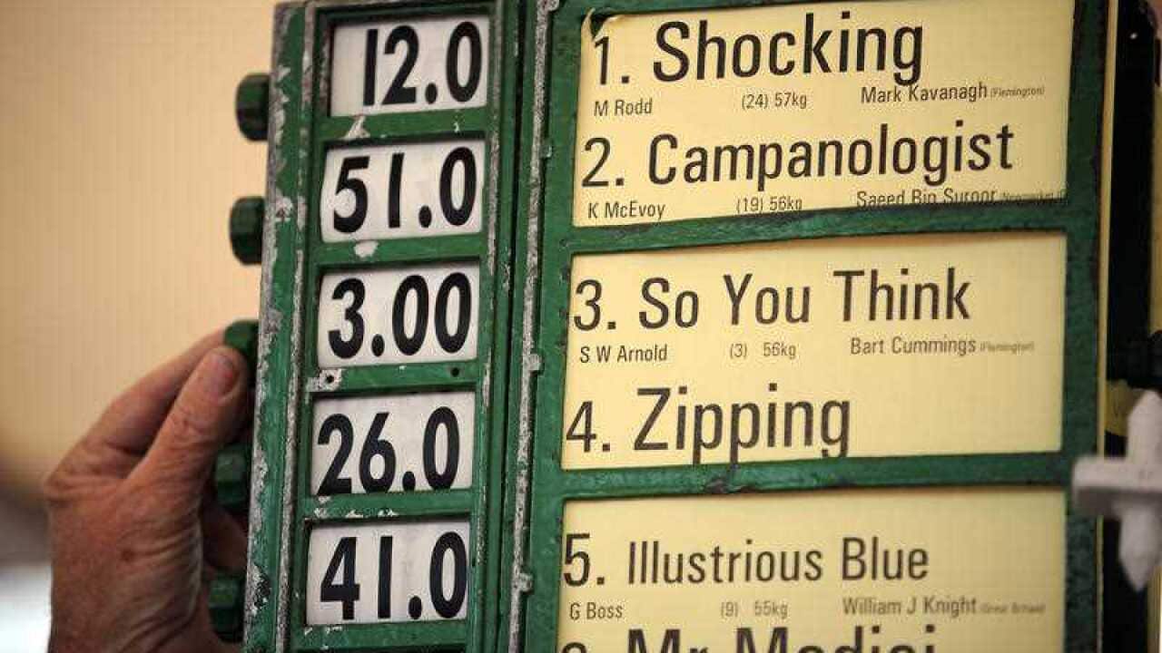 A bookie makes an early prediction on race favourites before the start of racing at Flemington racecourse, Tuesday, Nov. 2, 2010. The highlight of the day is the $6 million Melbourne Cup. (AAP Image/Joe Castro)