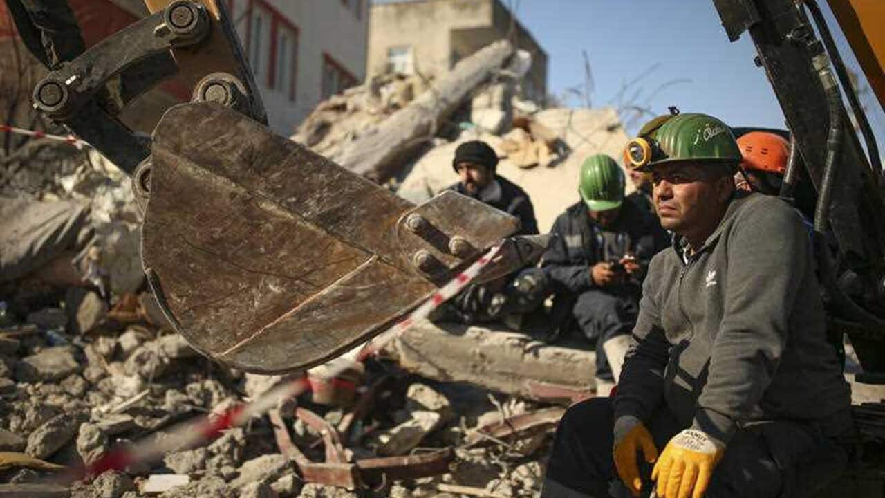 Rescuers stand by a collapsed building in Türkiye