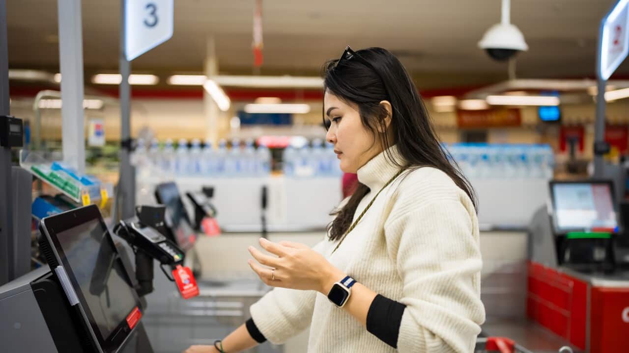 Female checkout by automatic payment machine in supermarket