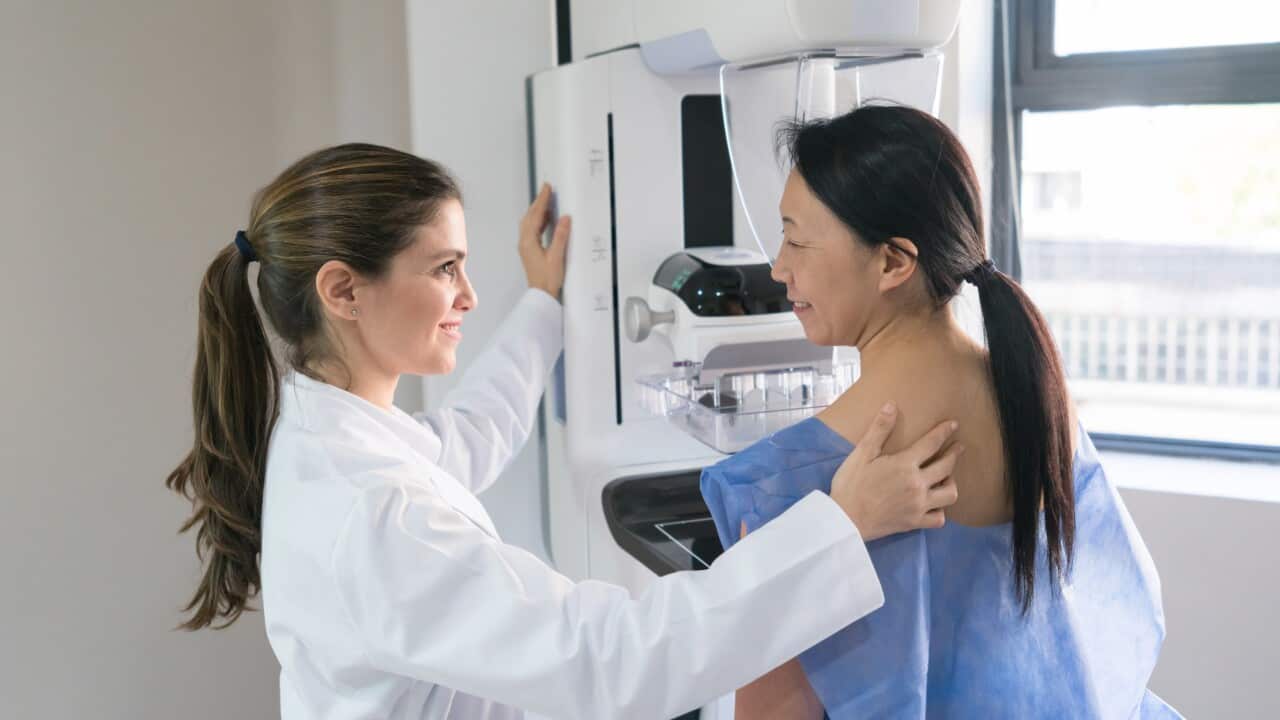 Female gynecologist helping a patinet get in posicion for a mammogram