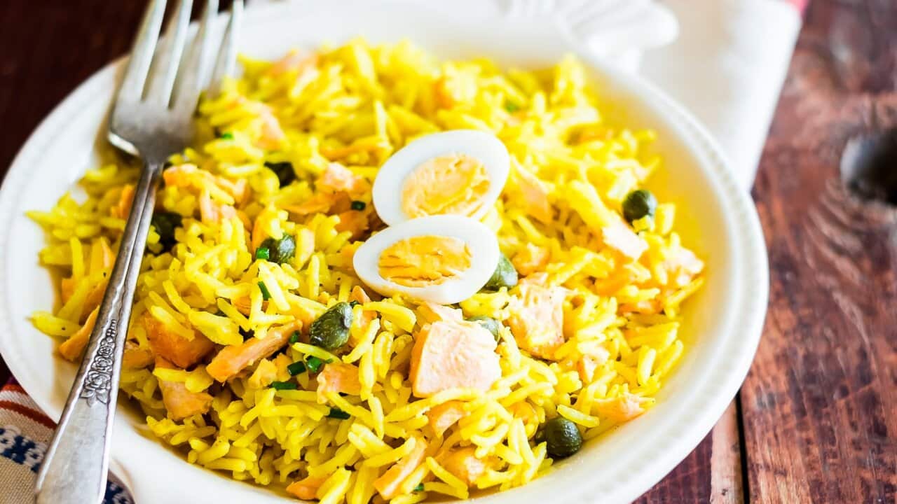 National scottish dish kedgeree with roasted basmati rice, curry powder, eggs and fish in a plate on a wooden table, selective focus. Image with copy space.