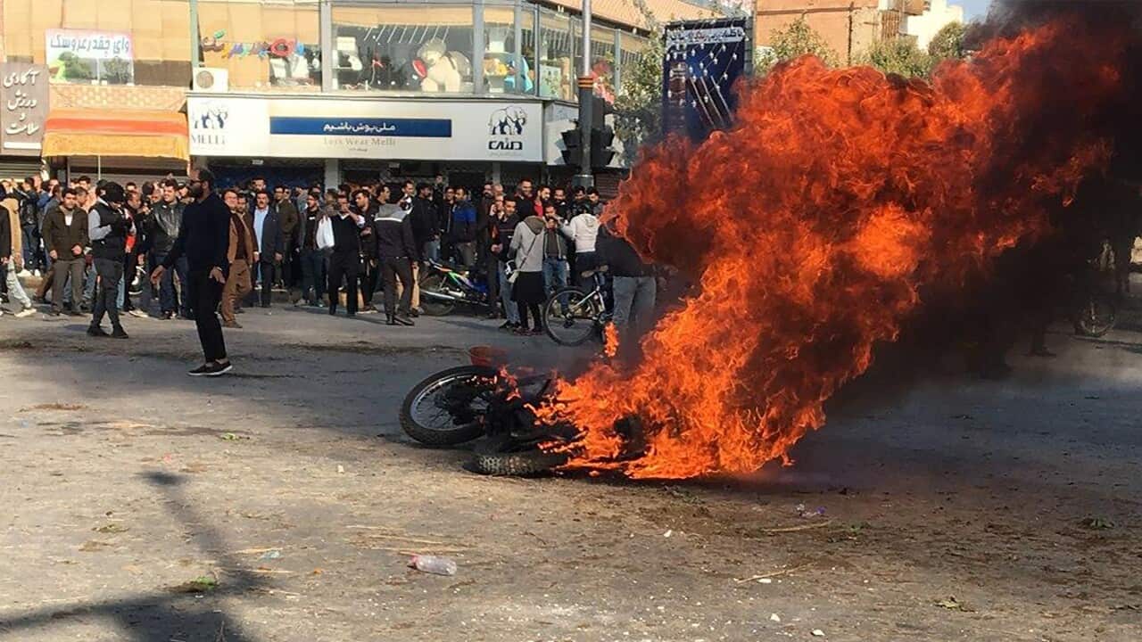 Iranian protesters gather around a burning motorcycle during a demonstration against an increase in gasoline prices.