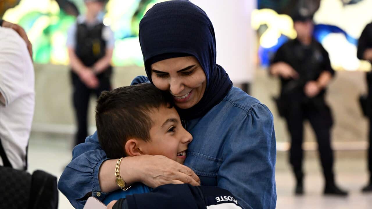 A woman and a young boy embrace and smile