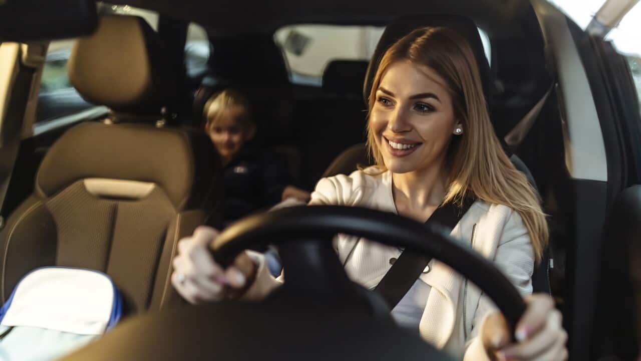 Happy single mother and her son testing new car in a showroom