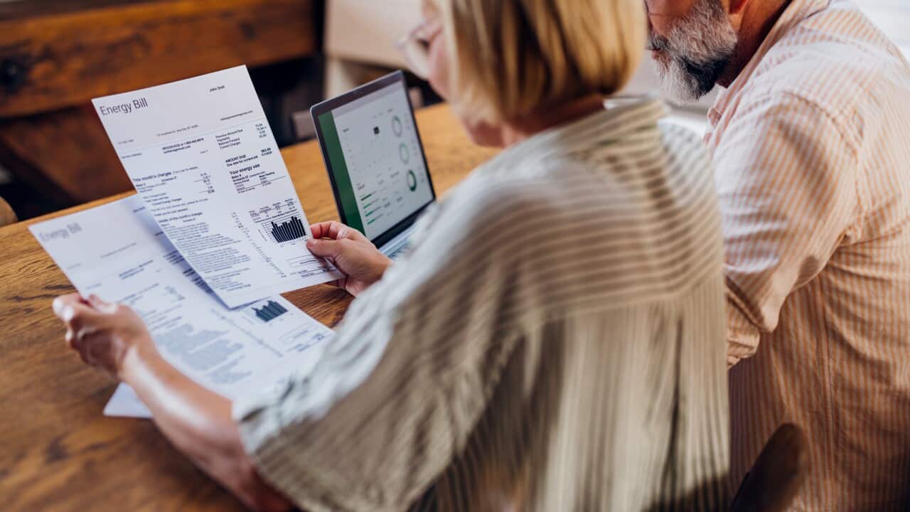 A senior couple sitting at a table looking at energy bills