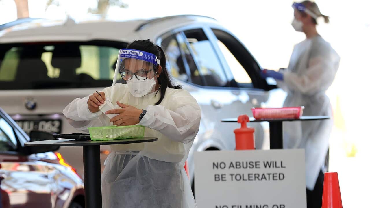 A health worker is seen as members of the public are seen queuing in their cars at a drive-through COVID-19 testing site at IPC Health Wyndham Vale, in Melbourne, Wednesday, December 29, 2021.