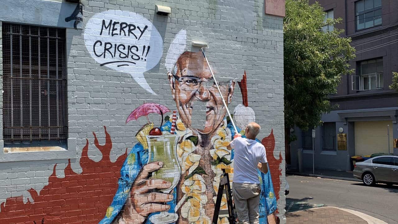 A man is seen painting over the mural of the prime minister.