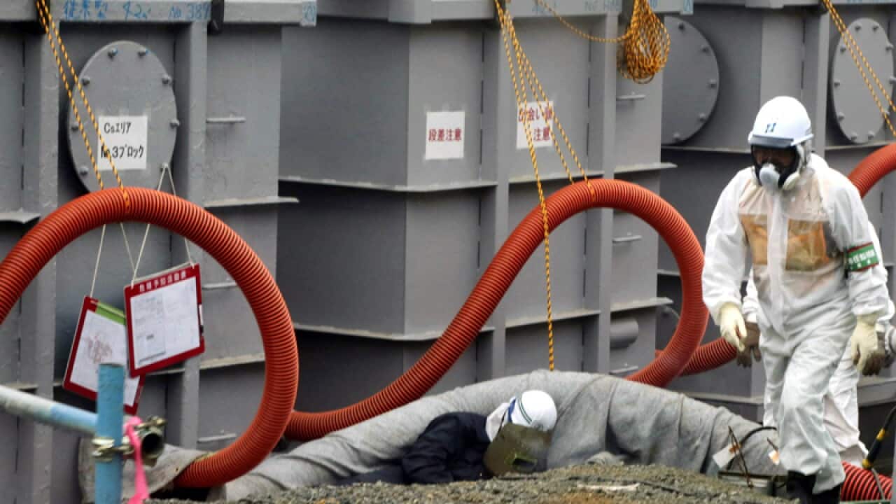 A worker in protective clothing works around tanks