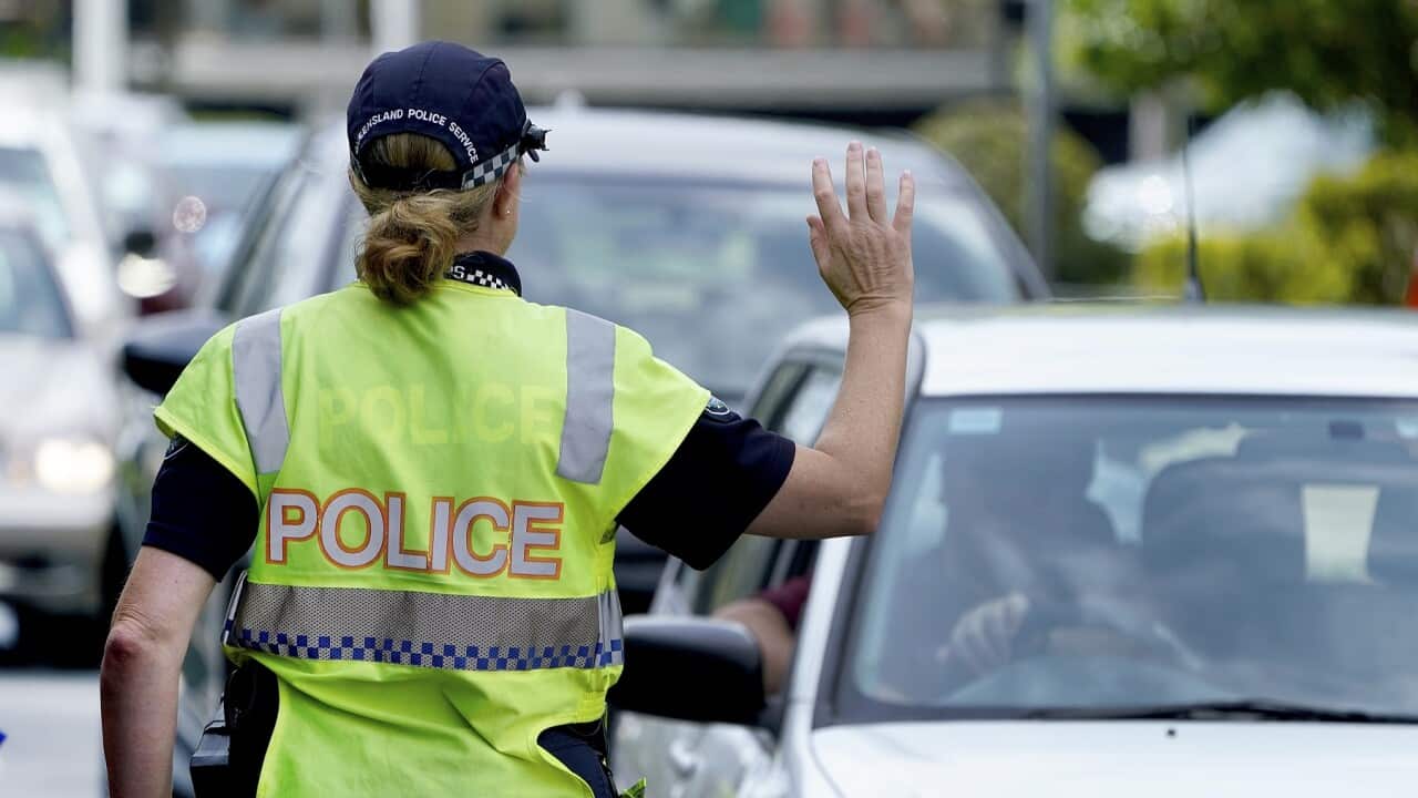 A police officer stops a driver at a checkpoint at Coolangatta on the Queensland - New South Wales border, Thursday, April 9, 2020. The Queensland Government is introducing new border control measures effective Friday where Queenslander residents crossin