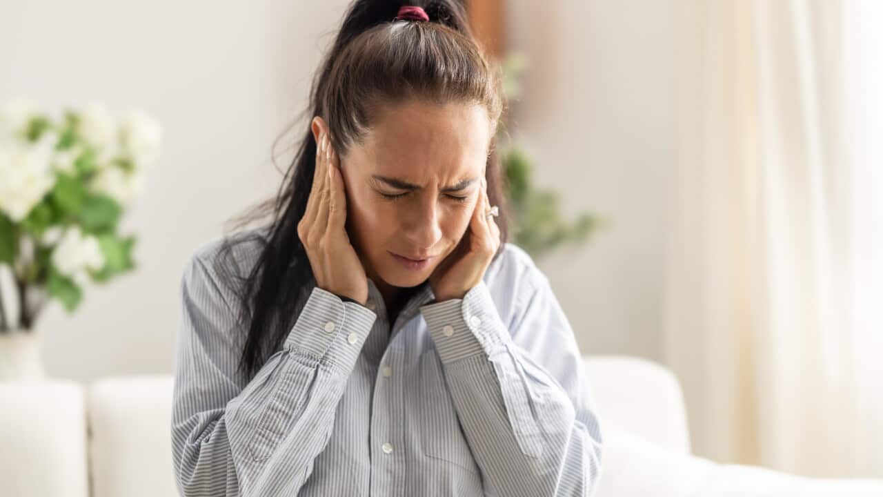 Young woman have headache migraine stress or tinnitus - noise whistling in her ears.