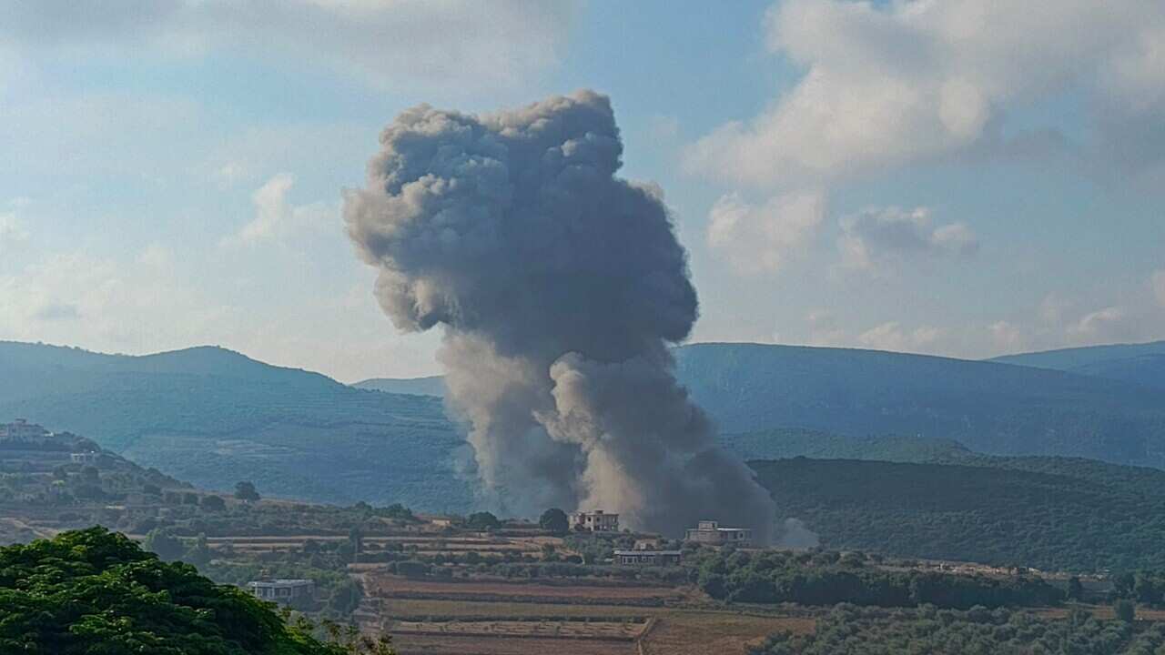 Smoke billows into the sky from a field