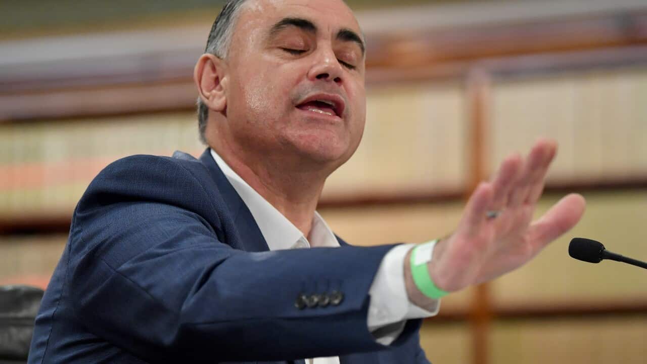 A man sitting down and speaking into a microphone.