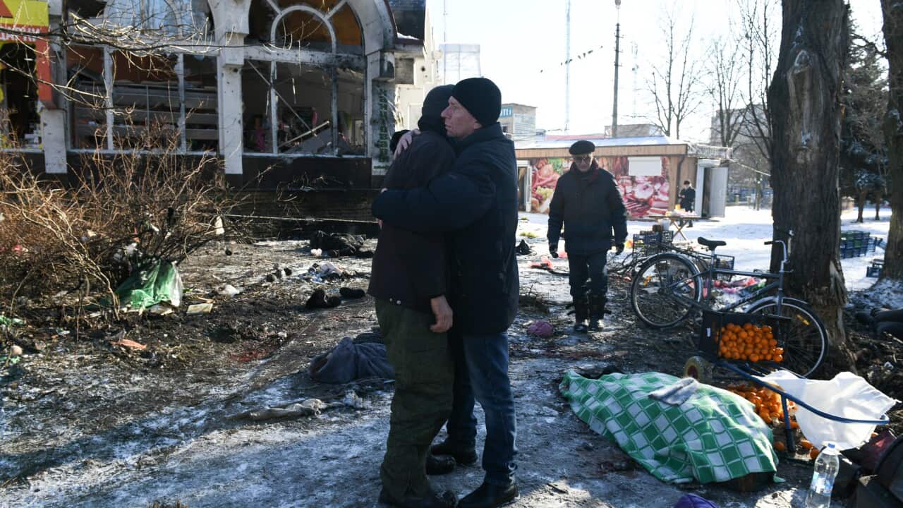 Two people hugging amid rubble