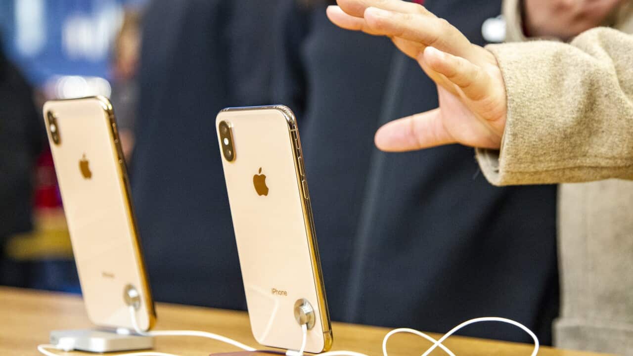 A hand reaching for a mobile phone