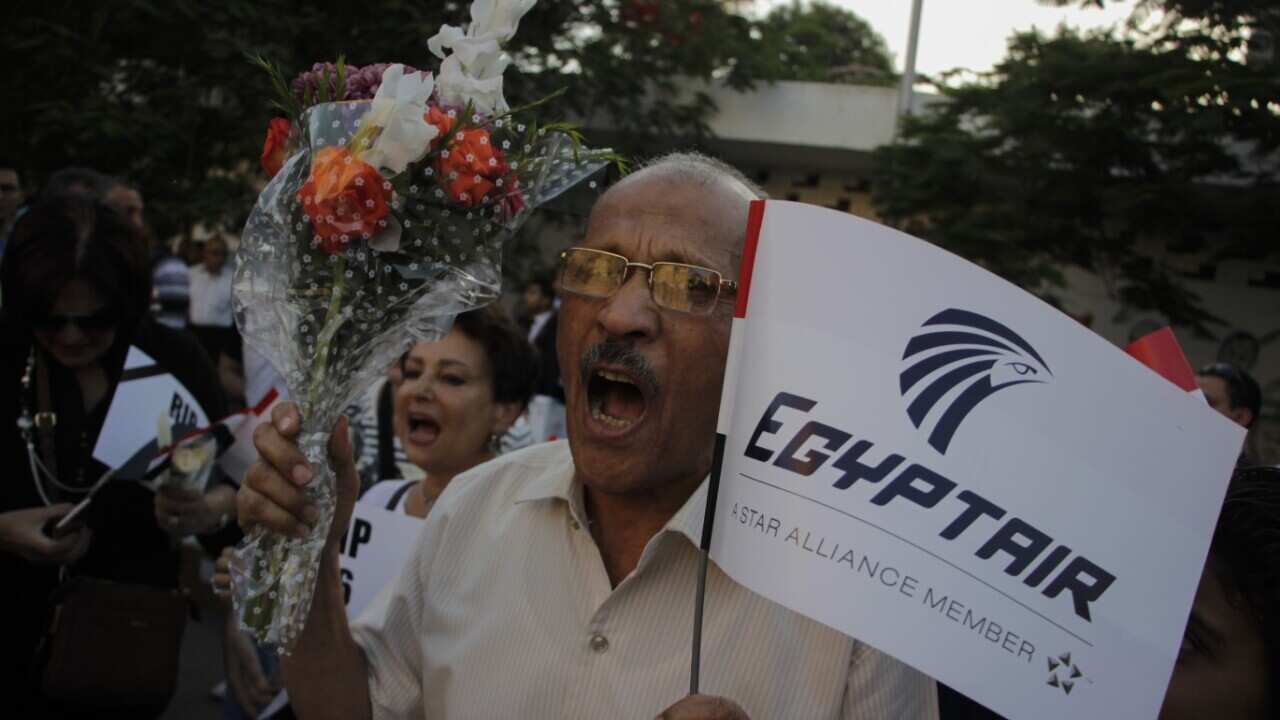A man holds an EgyptAir flag and flowers May 26, 2016 at a vigil for the victims of the recent air disaster
